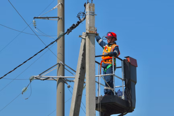 A person checking wires and other electrical elements on a poll.