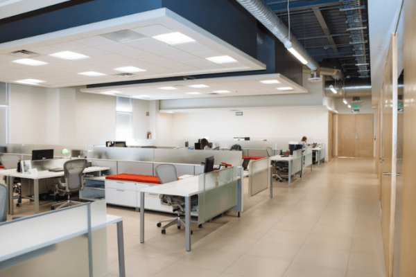 An empty office with bright white lights on the ceiling.